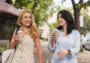 two women walking with a coffee and chatting