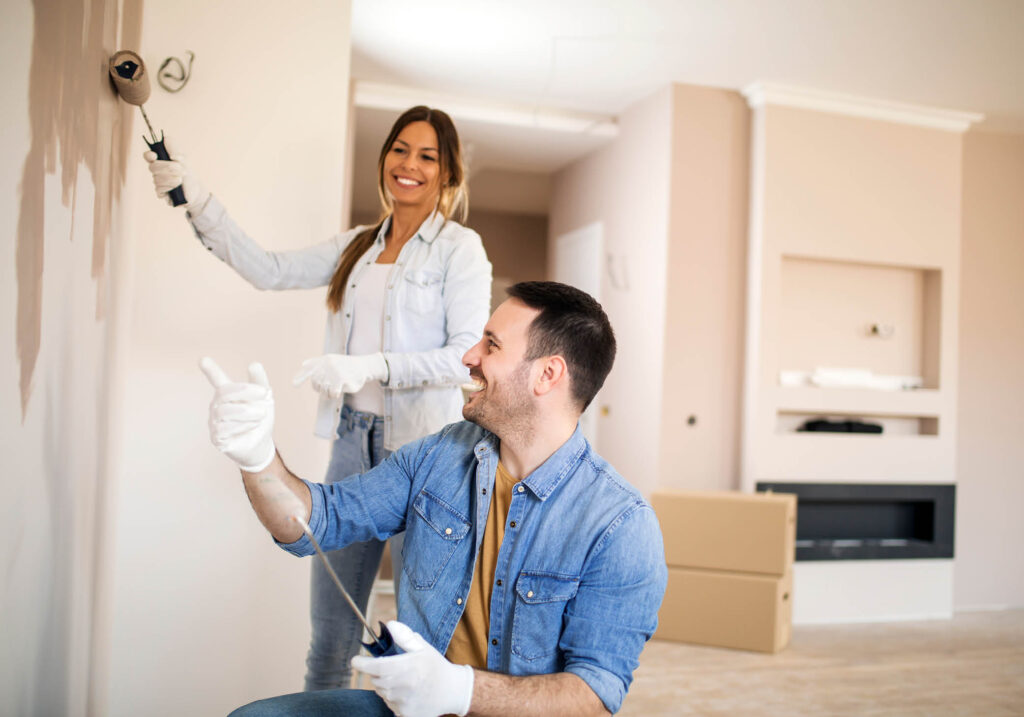 Couple painting a wall and smiling