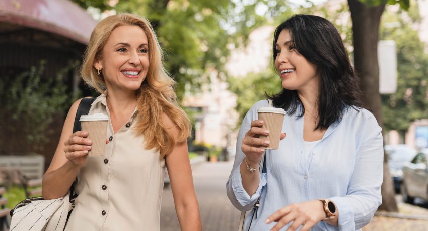 two women walking with a coffee and chatting